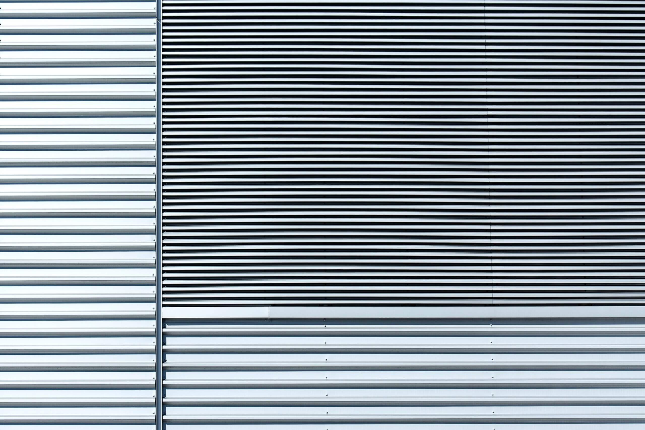 Nahaufnahme einer Aluminiumwand, die ein minimalistisches Design mit horizontalen Streifen und metallischer Textur zeigt.