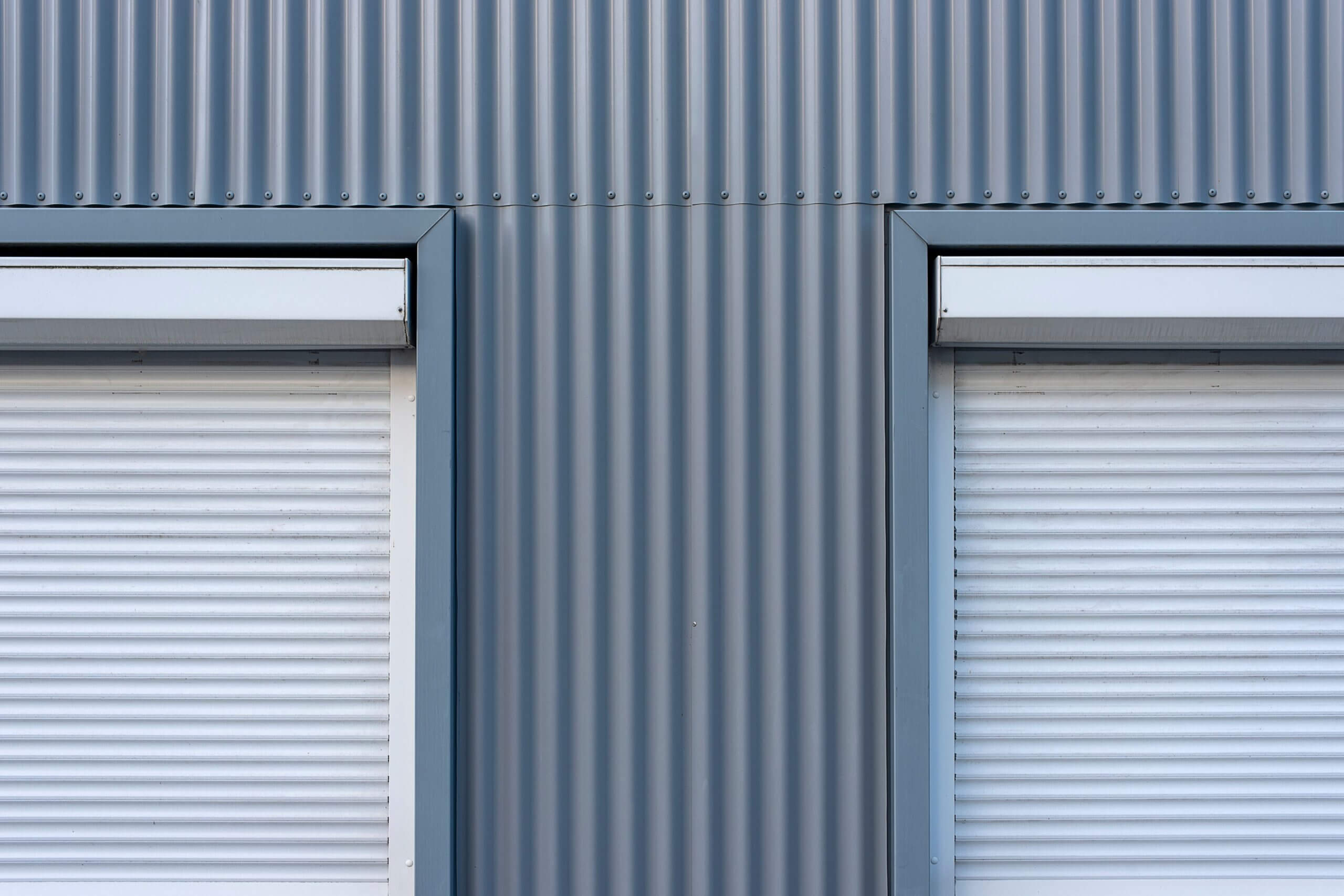 Doppelte Rollläden im Industriestil an einer Wellblechwand für einen eleganten, modernen Look.