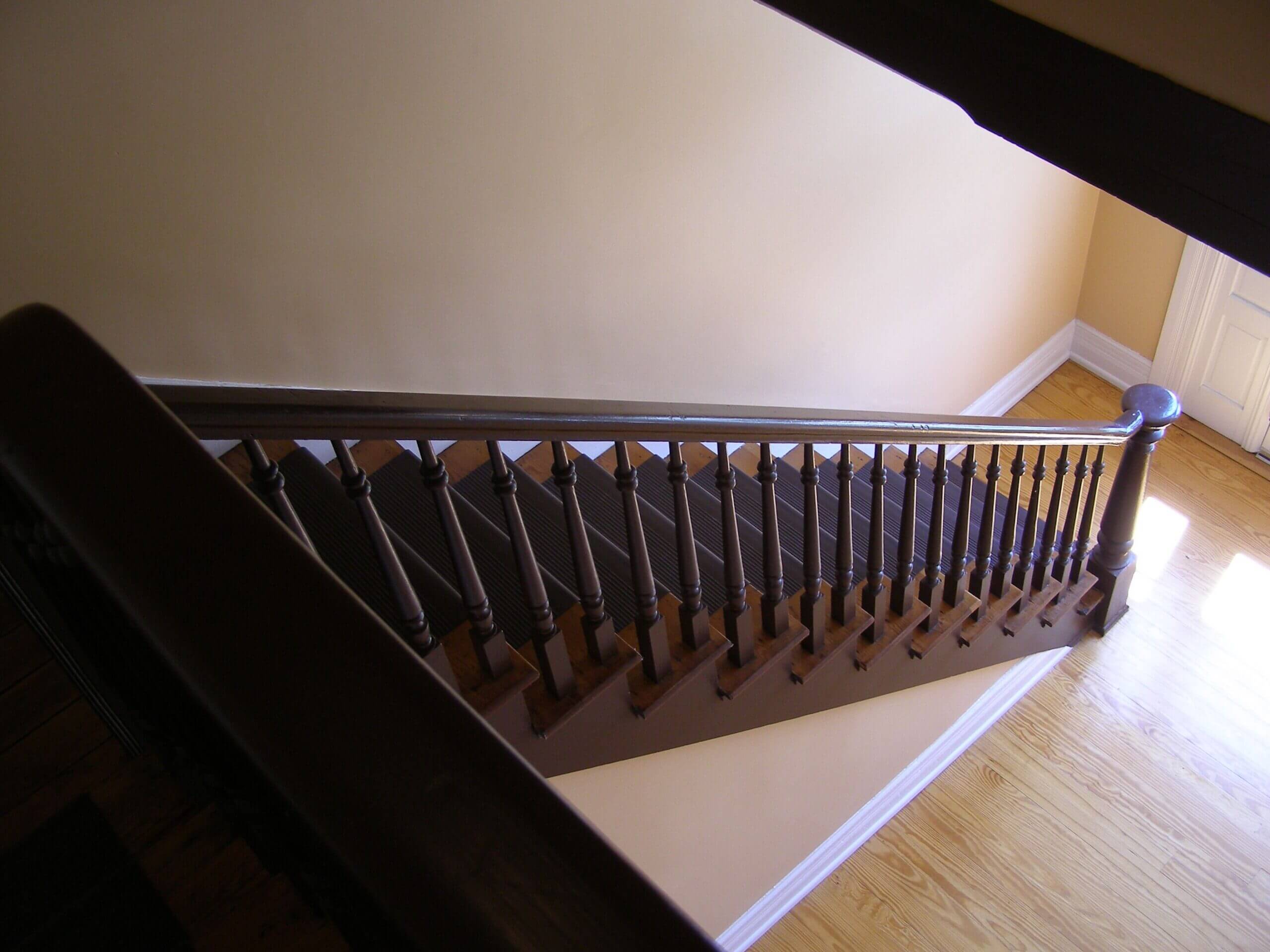 Charming wooden staircase with a detailed handrail inside a home, offering a warm and inviting ambiance.