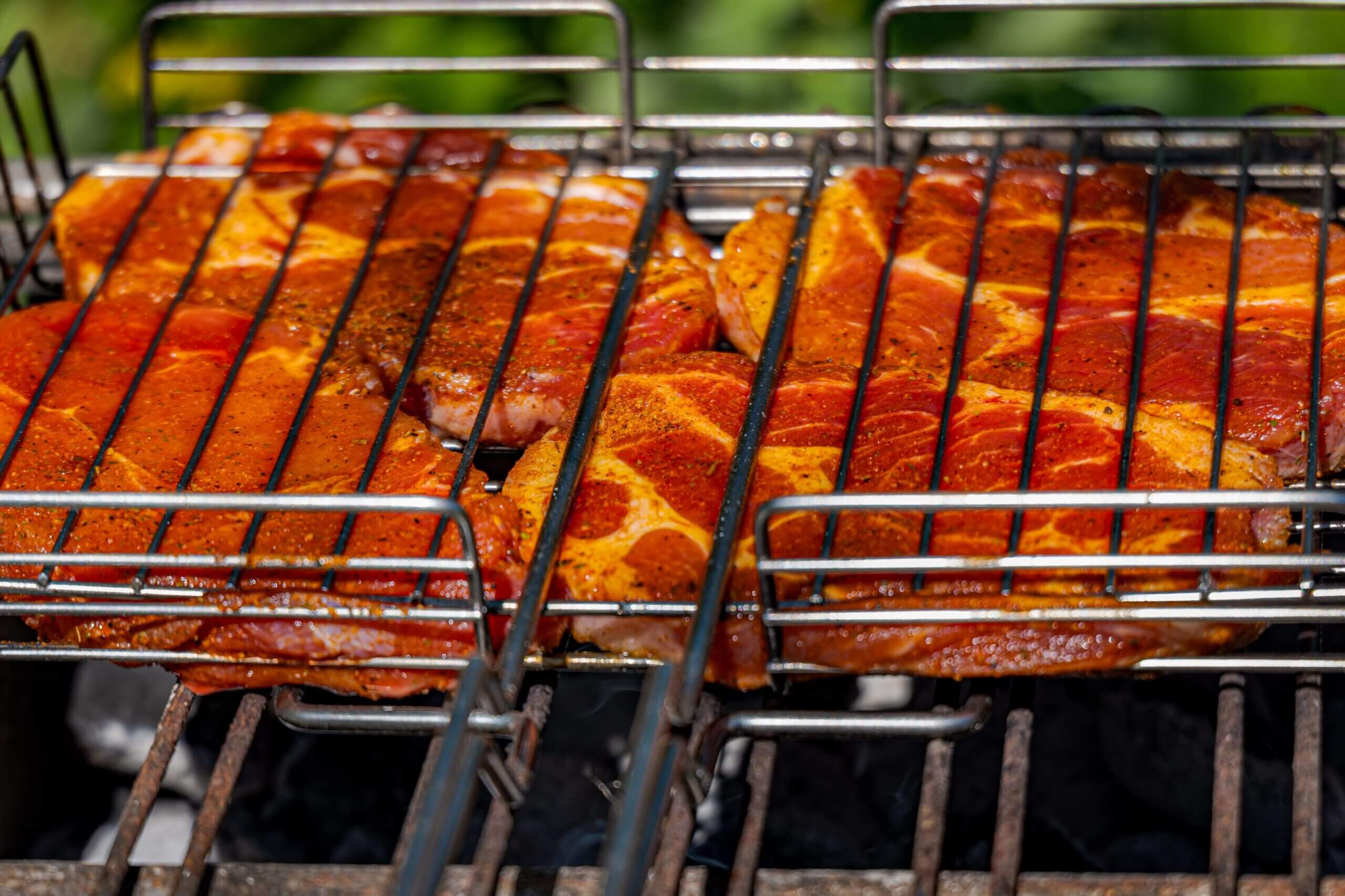 Juicy, seasoned meat sizzling on an outdoor barbecue grill, perfect for a summer cookout.