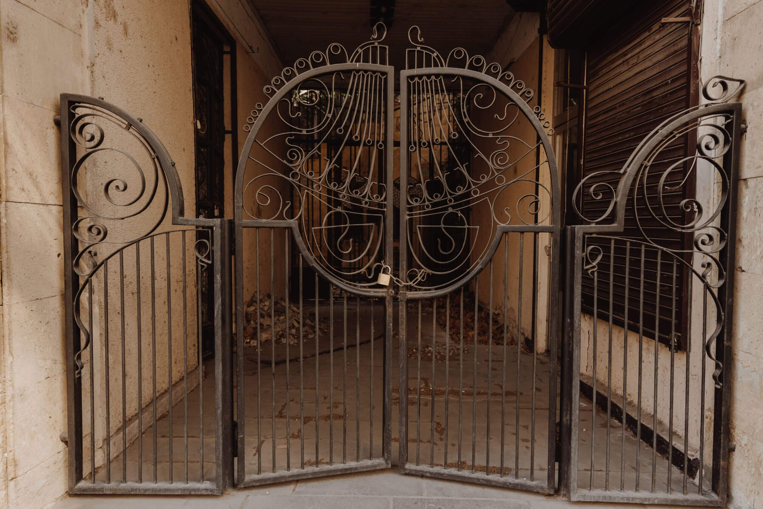 Intricately designed metal gate featuring vintage scrollwork and artistic flourishes, adding charm to an outdoor setting.