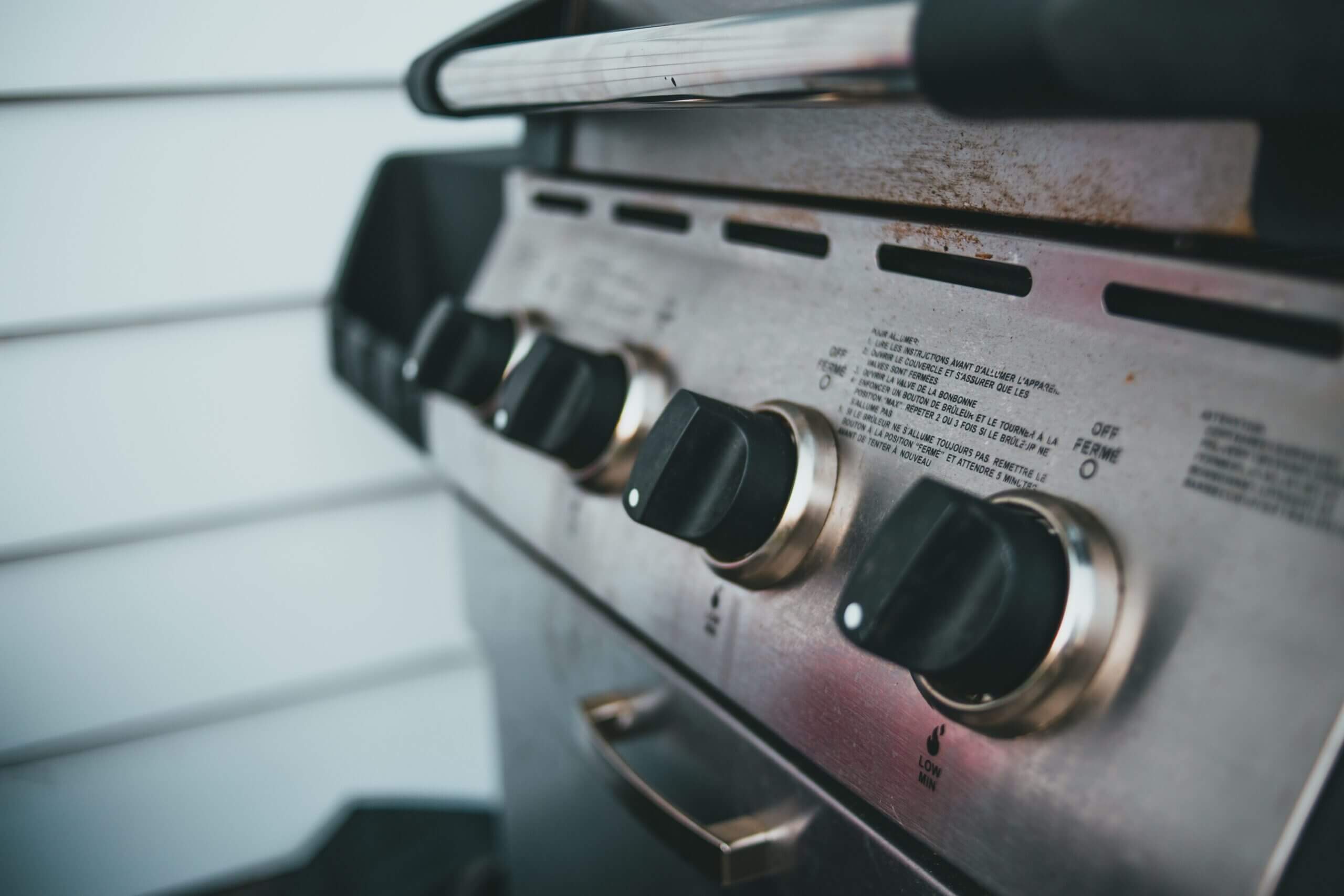 Detailed view of barbecue grill controls, showcasing knobs and stainless steel surface.