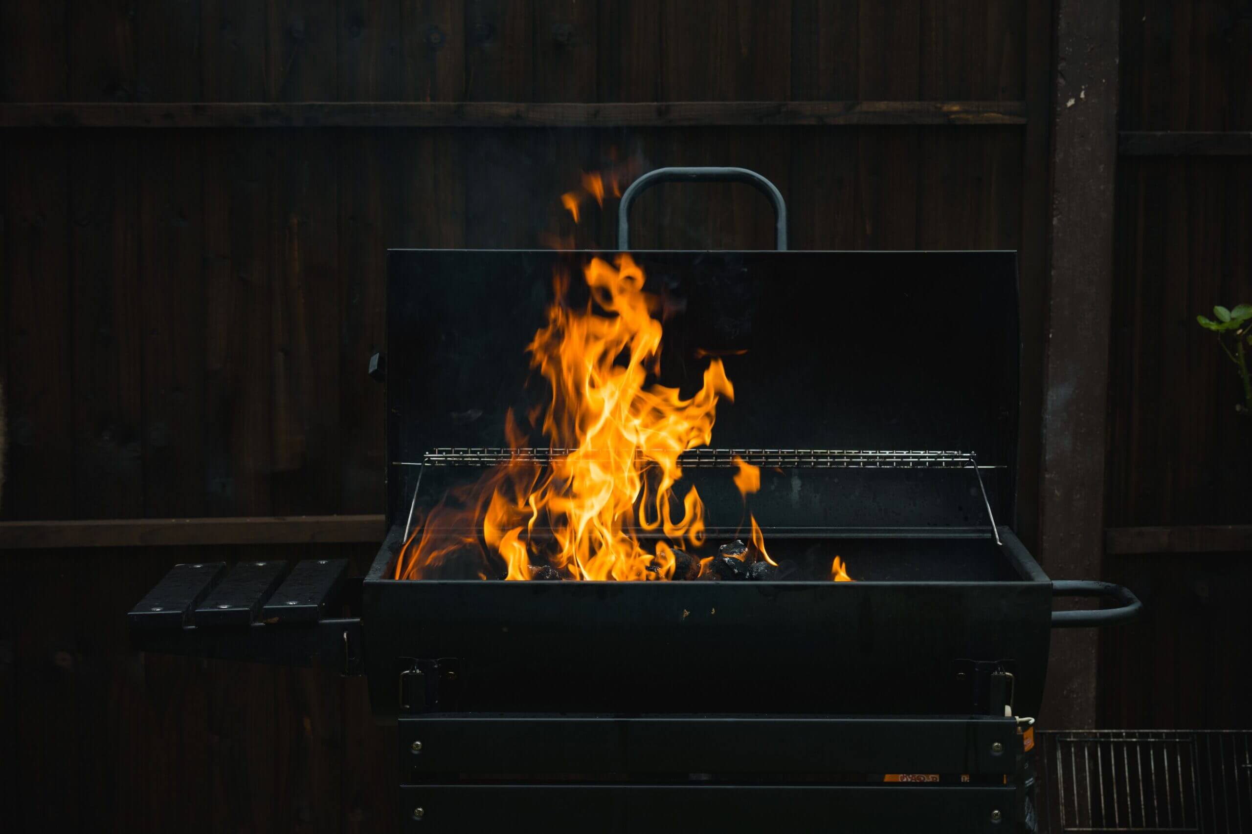 A close-up of an outdoor barbecue grill with blazing flames over charcoal, perfect for summer grilling.
